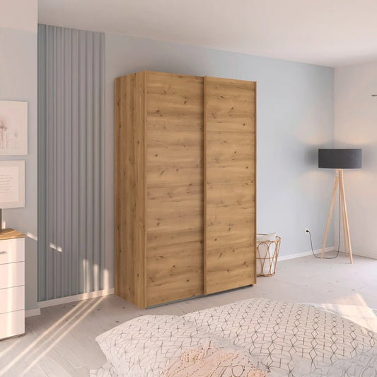 Small 137cm Rauch Wooden wardrobe in a bedroom with light blue walls and a bed in the foreground.