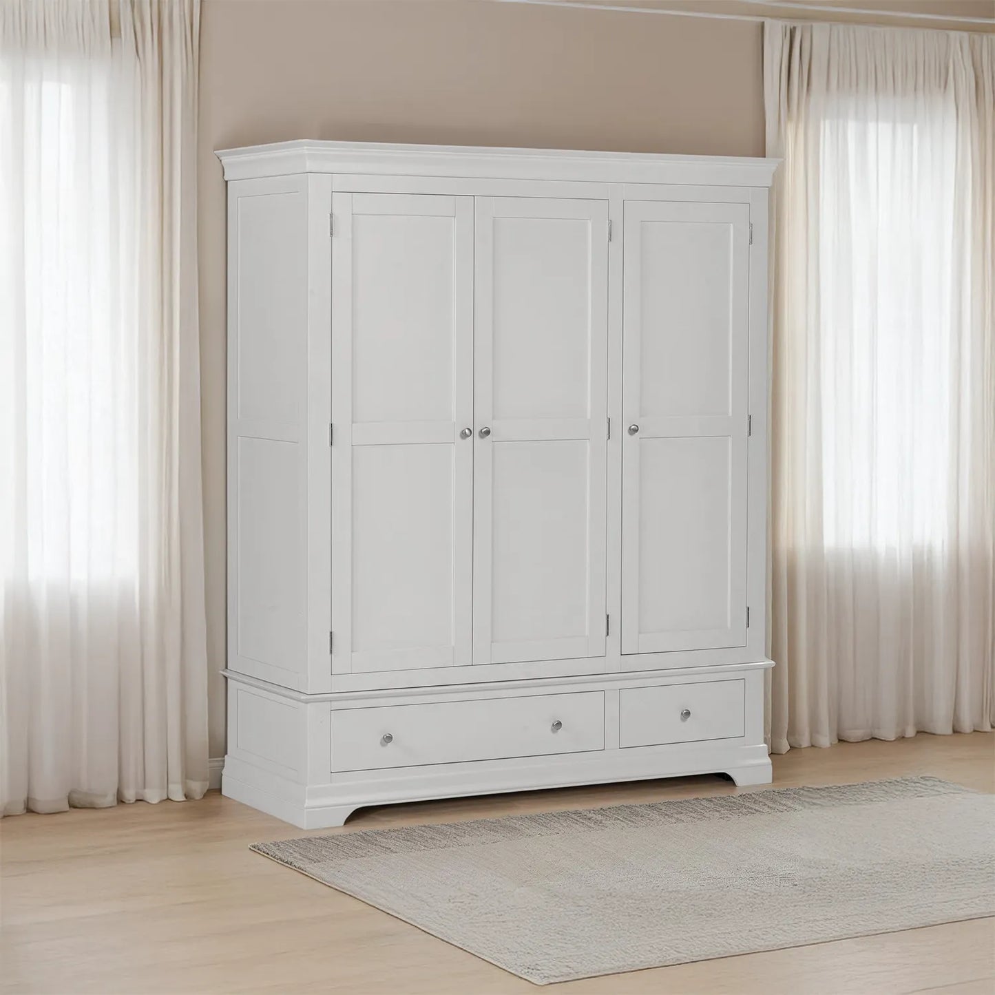 Grey wardrobe with two doors and two drawers in a room with light-colored curtains and wooden floor.