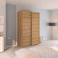 Small 137cm Rauch Wooden wardrobe in a bedroom with light blue walls and a bed in the foreground.