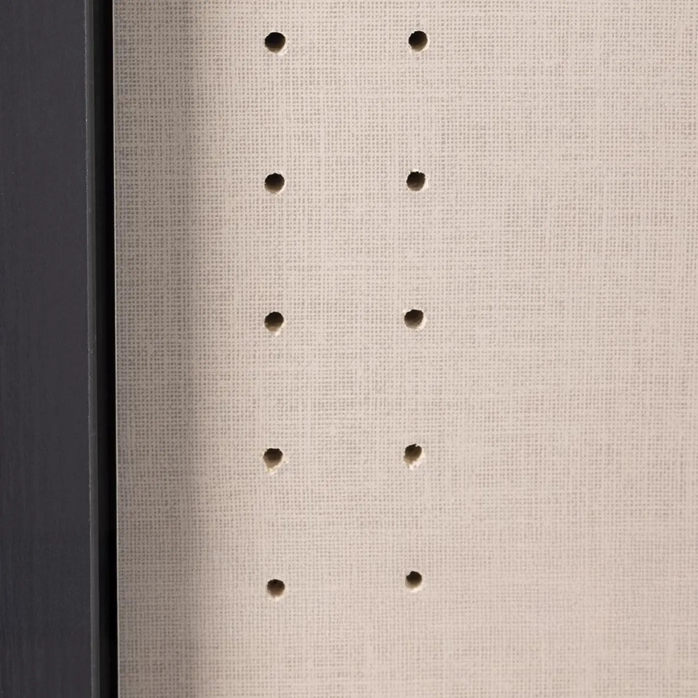 Close-up of a textured beige surface with small holes arranged in a vertical pattern in wardrobe