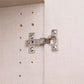 Metal cabinet hinge on a Rauch wardrobe cabinet door with pre-drilled holes.