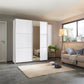 Modern bedroom with a large white wardrobe, beige sofa, and decorative items.