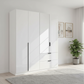 A modern white high-gloss wardrobe with mixed door styles and two drawers, shown in a bright, minimalist bedroom setting with a potted plant and framed wall art.