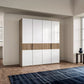 Modern wardrobe with white doors and wooden accents in a room with a rug and side table.