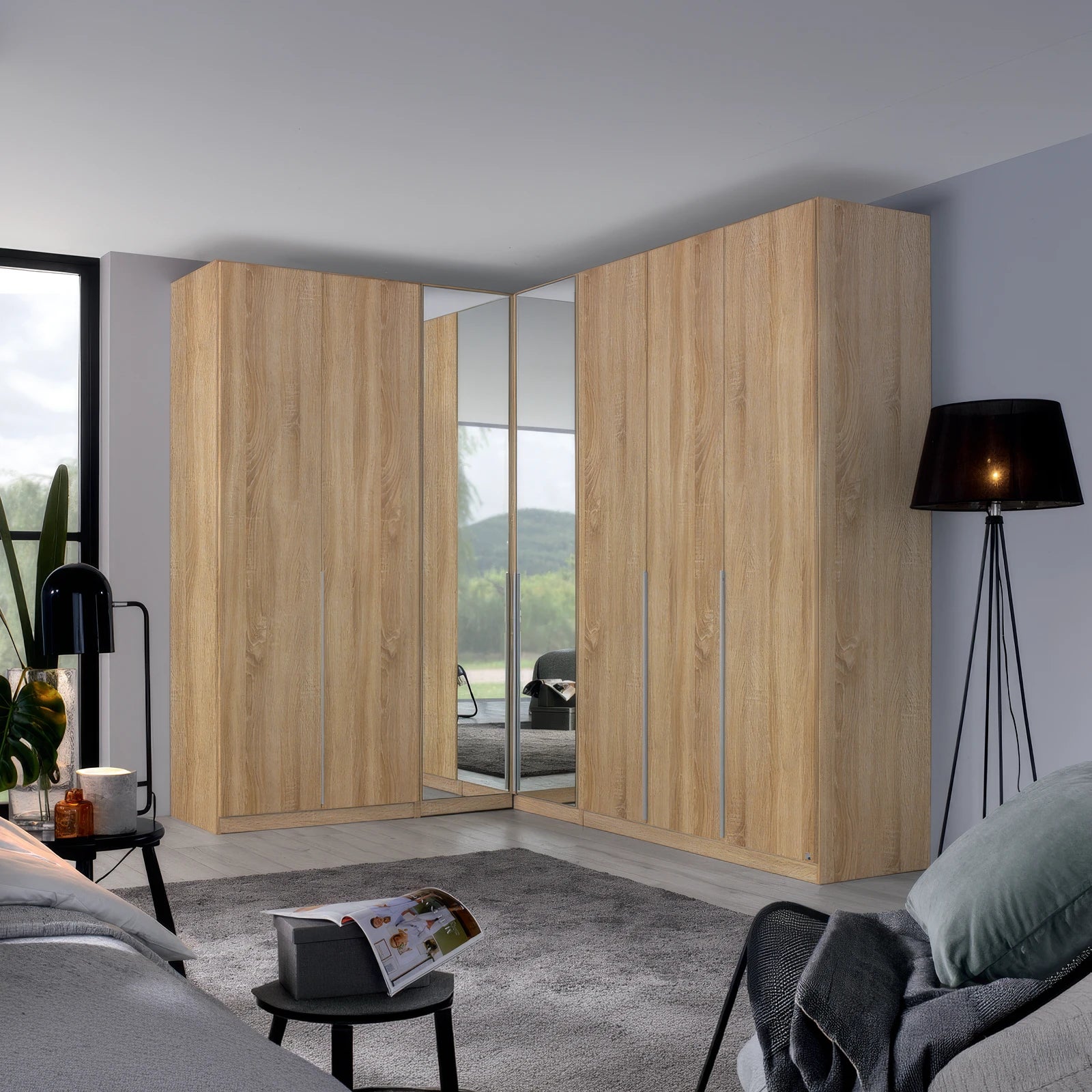 A large corner wardrobe set in a modern bedroom, featuring light oak wood grain doors with mirrored panels on the inner doors to show the bed underneath.