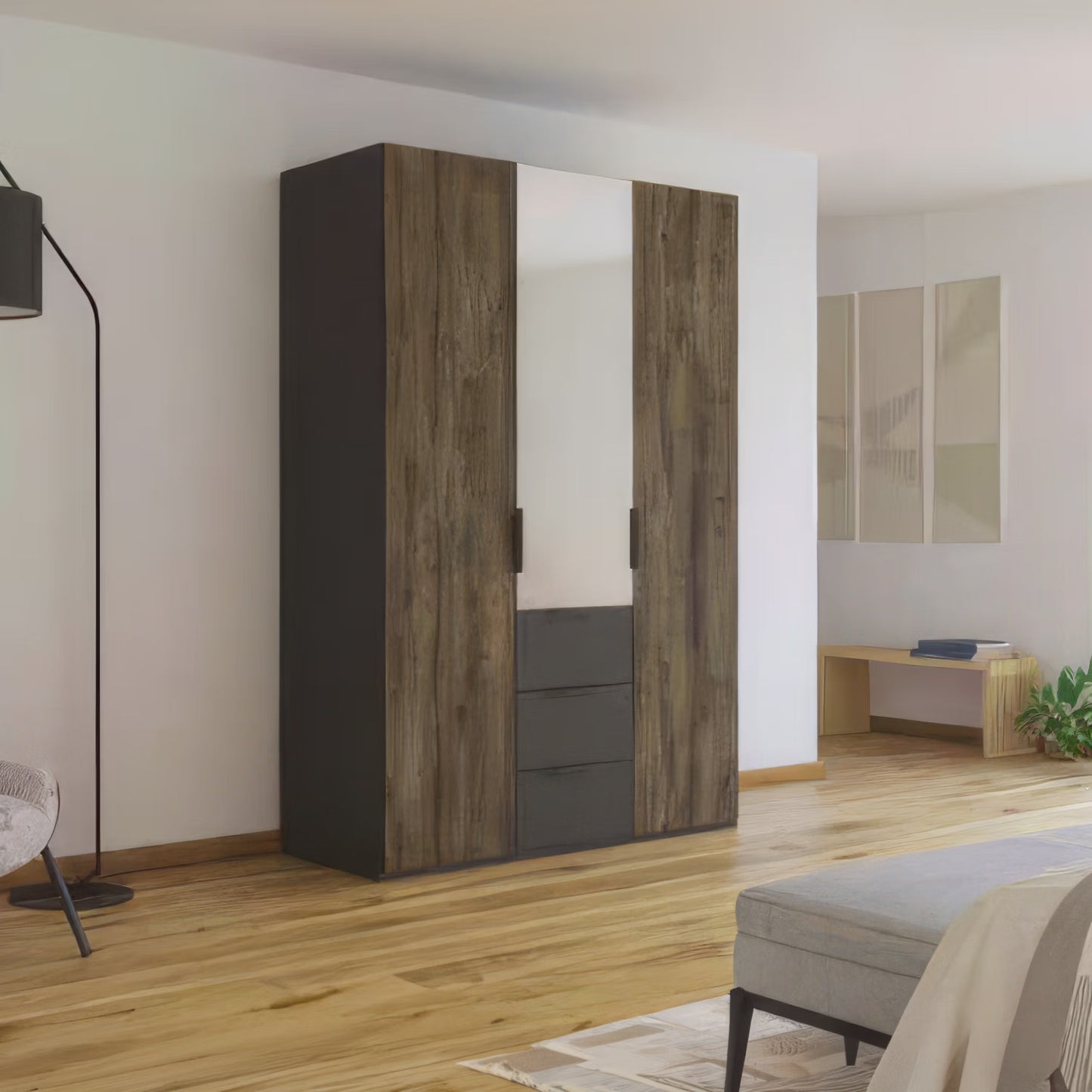 A tall Rauch Fifty Atlantic Oak three-door wardrobe with two Dark wood-grain doors and one mirrored door and three exterior drawers set against a white wall in a modern bedroom with light wood floors.