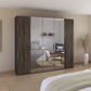 A large modern wardrobe with dark brown wood-grain doors and three mirrored sliding doors, shown in a styled bedroom setting.