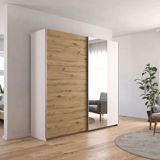 Rauch Aurelia Artisan Oak Sliding Door Wardrobe with Mirror in White Carcase styled in a modern bedroom
