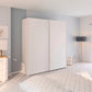 Modern bedroom with a large white wardrobe, light gray walls, and minimal decor.