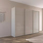 A modern three-door sliding wardrobe with glossy light beige doors, Rauch Kulmbach Formes shown in a minimalist bedroom setting with a wood floor and neutral wall.