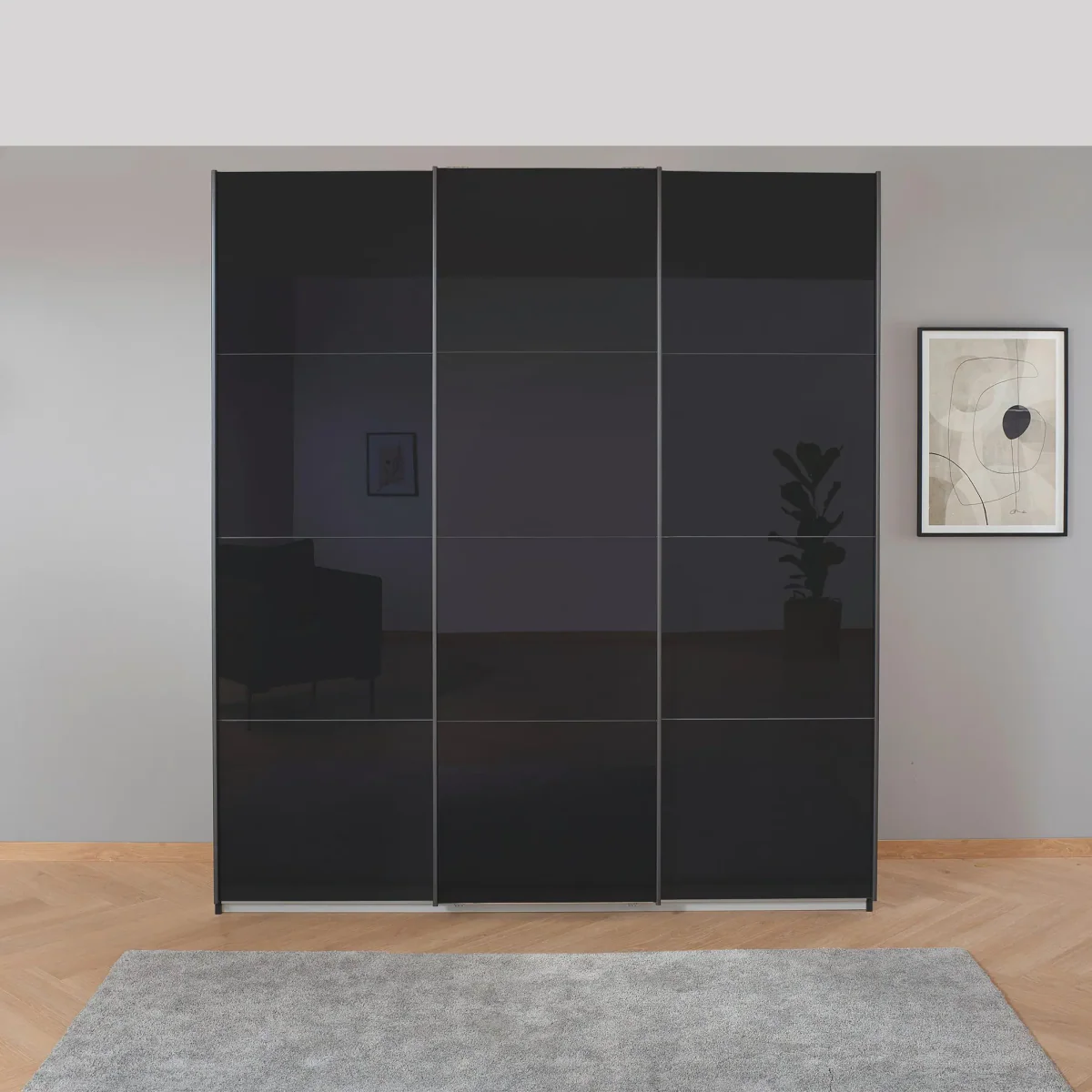 Black sliding wardrobe doors in a room with a gray wall and a framed picture.