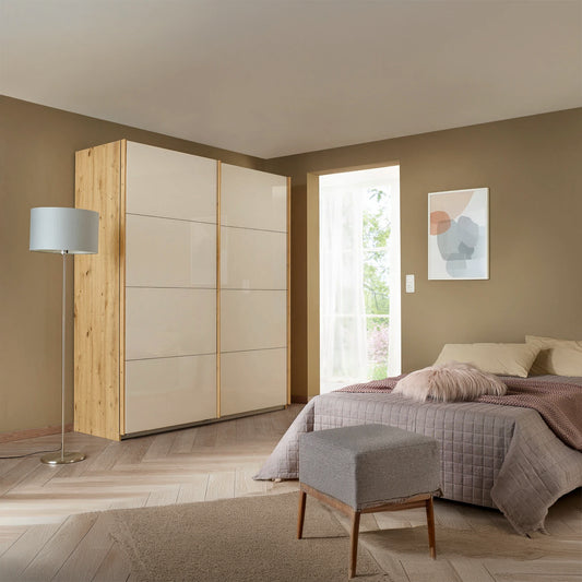 Rauch Freja Glass Door Sliding Wardrobe in Champagne front with Oak Carcase styled in a modern bedroom