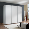 A modern Low height Wiemann Darwin three-door sliding wardrobe with matte white doors, set in a contemporary living room with dark gray and beige walls, wood flooring, and a white rug.