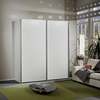 A modern white Wiemann Darwin 197cm High sliding wardrobe with slim metallic frames, set in a styled living room next to a sofa and window.