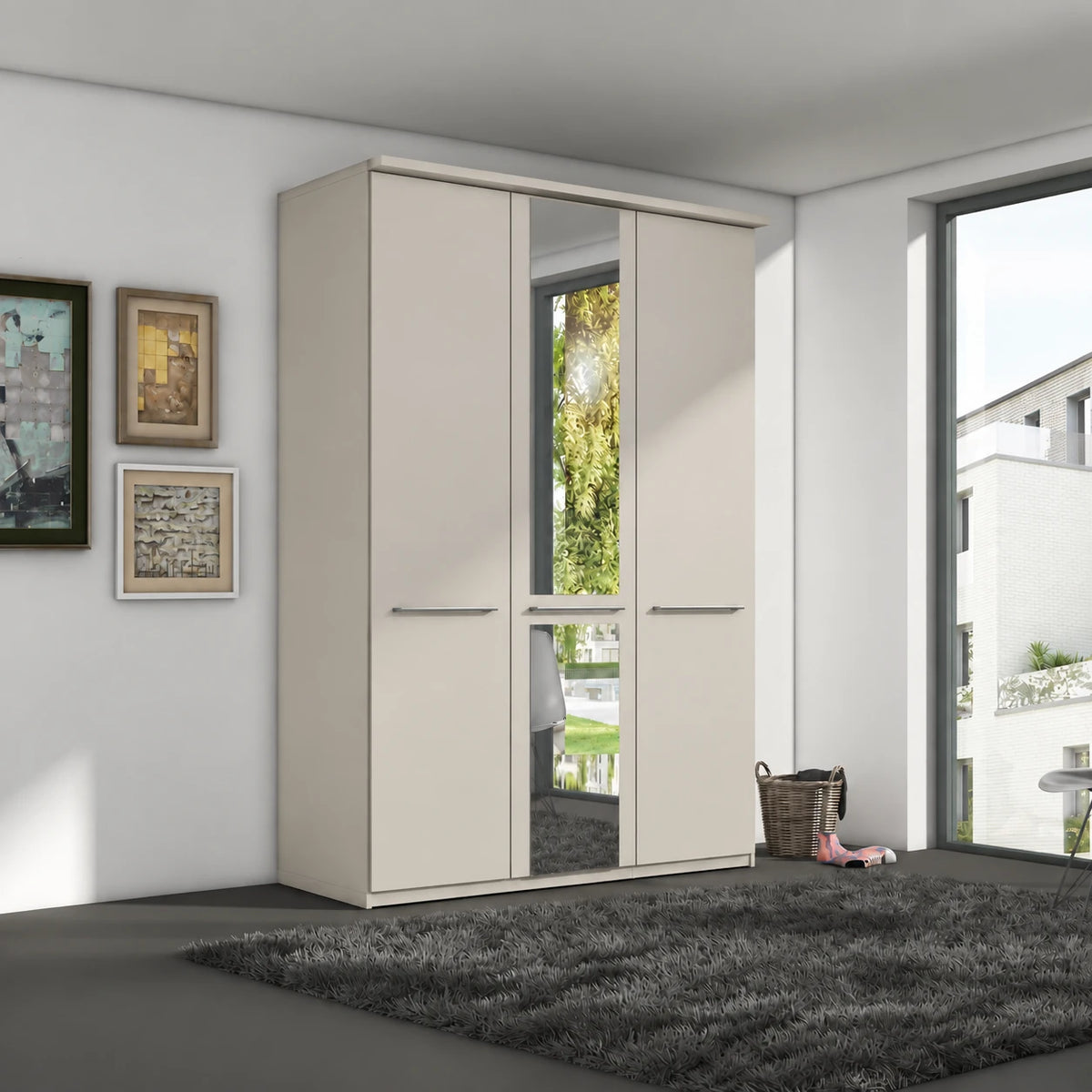 A modern 3-door Wiemann Cairns wardrobe with a mirrored door and two solid doors in a light beige finish, set in a contemporary room with a dark gray shag rug and framed wall art.