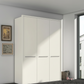A modern three-door Wiemann Cairns wardrobe with Passepartout Frame  in a clean, minimalist room with light gray walls, framed wall art, and a window on the right.