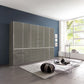 A large modern wardrobe or closet system with glossy Havana Glass doors and drawers, installed against a dark blue wall in a contemporary living room with a window, rug, and coffee table.