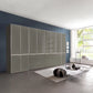 A large modern wardrobe or storage cabinet set in a styled living room. The cabinet features a glossy light gray finish with a grid pattern on the upper doors and multiple drawers on the lower section.