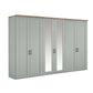 A long Wiemann Truro wardrobe or storage cabinet with six paneled doors in a muted sage green finish, including two central mirrored doors, a light wood top, and slim black handles, shown on a plain white background.