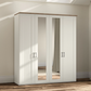 A tall white four-door Wiemann wardrobe with two mirrored doors and a light wood top, shown in a real room with beige walls, wood flooring, and soft sunlight streaming in.