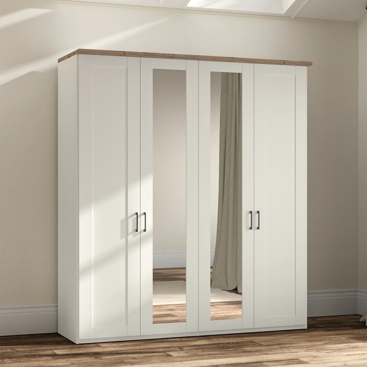 A tall white four-door Wiemann wardrobe with two mirrored doors and a light wood top, shown in a real room with beige walls, wood flooring, and soft sunlight streaming in.