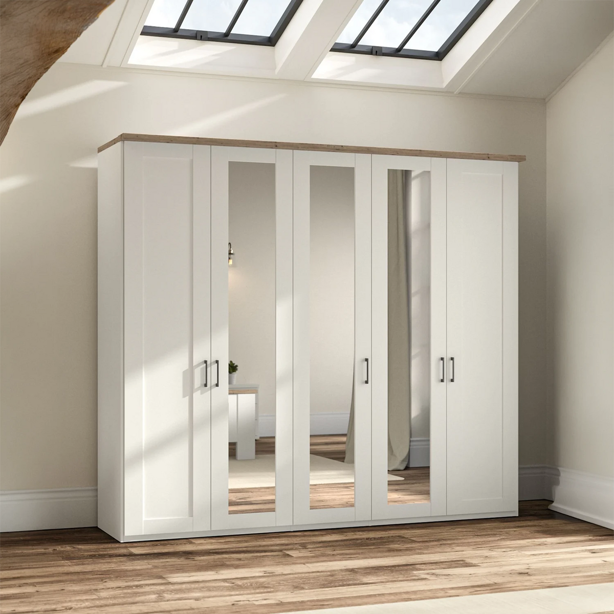 A large white five-door Wiemann Truro wardrobe with three mirrored doors and two solid doors, topped with a light wood grain surface, shown in a bright room with wood flooring and skylights.